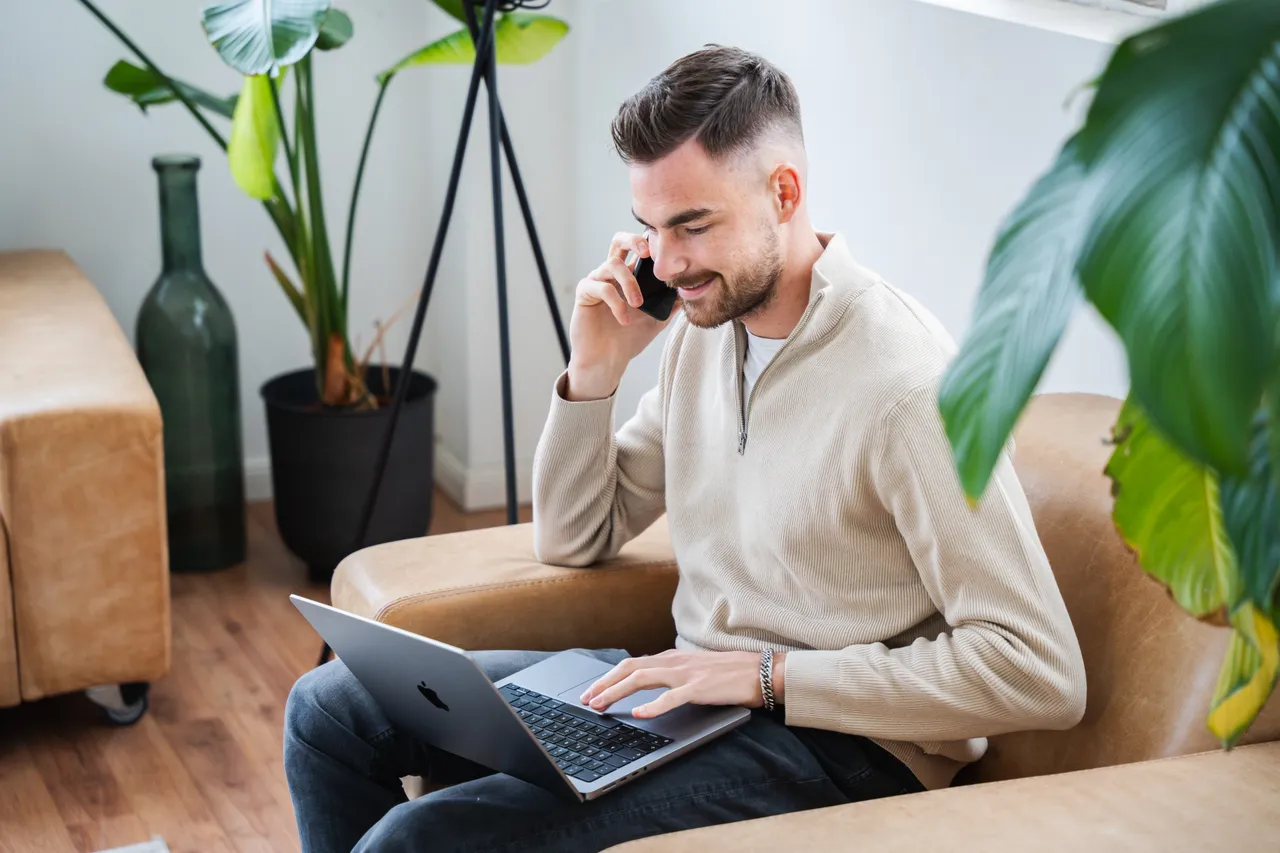 SEA-Freelancer Jan Philipps bei der Arbeit am Laptop, telefonierend auf dem Sofa